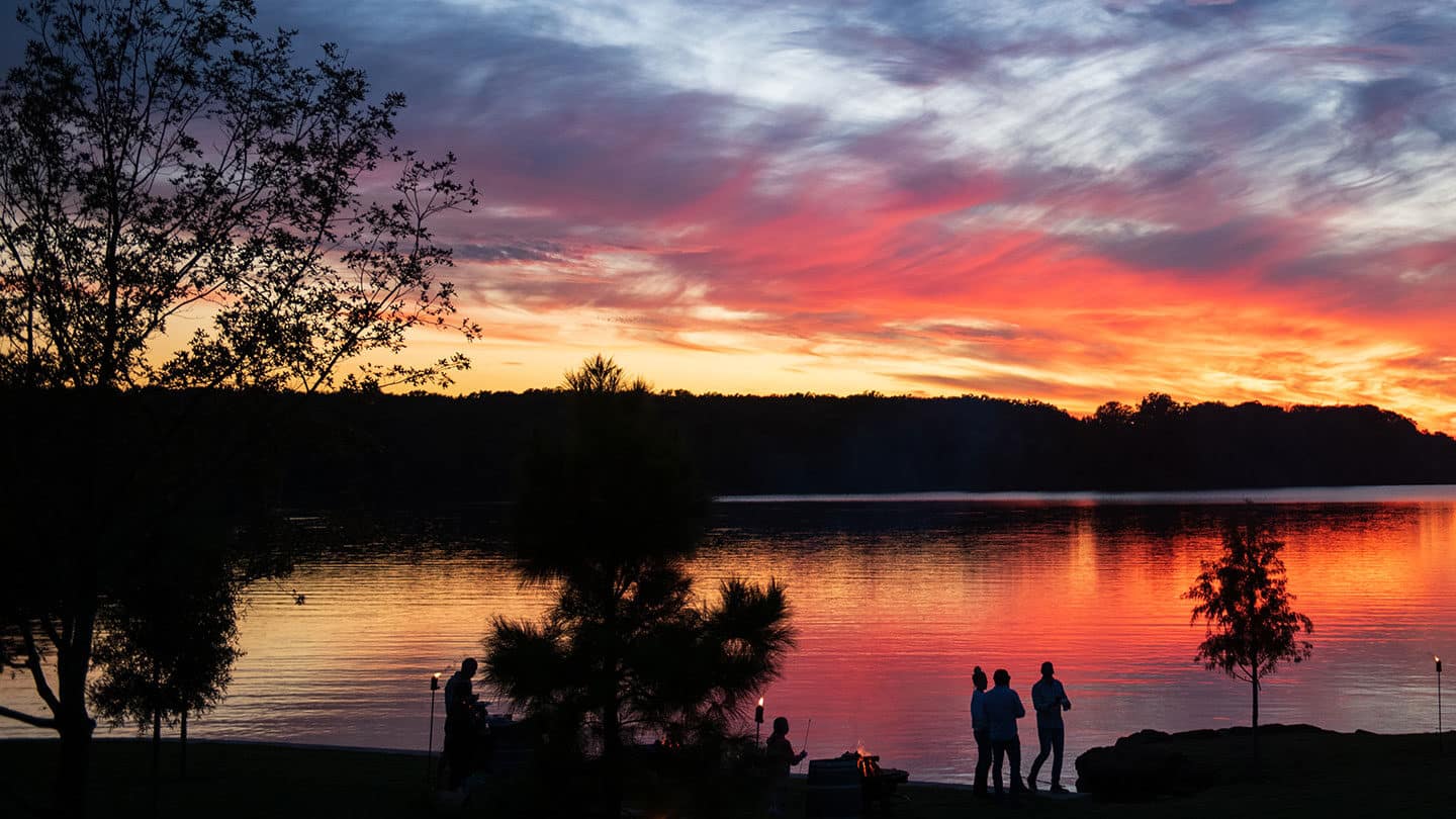 A sunset view of the Long Cove at cedar creek lake as family enjoys campfire