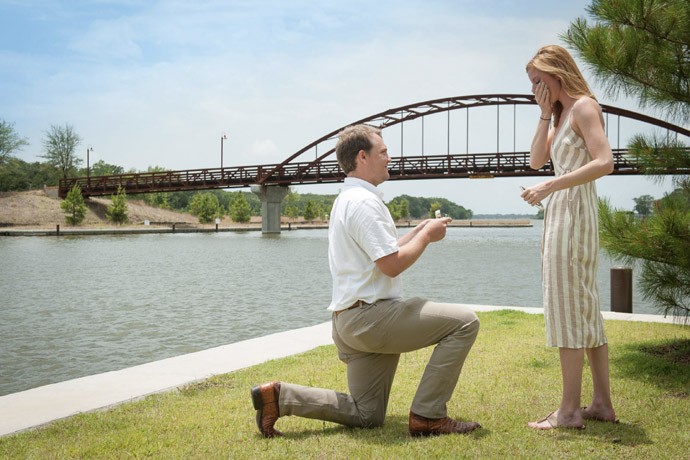 Man proposing to woman in front of the bridge at Long Cove Community