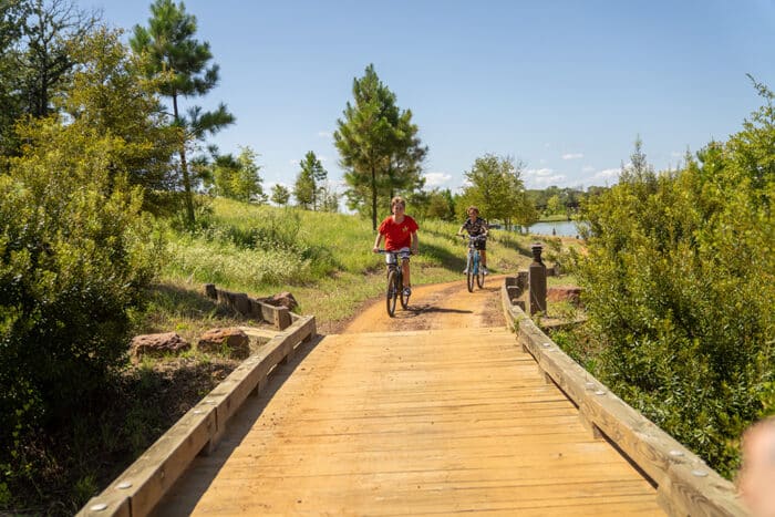 Children riding bikes on a hiking trail with lake in the background